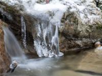 Figuren aus Eis an Fels im Bach